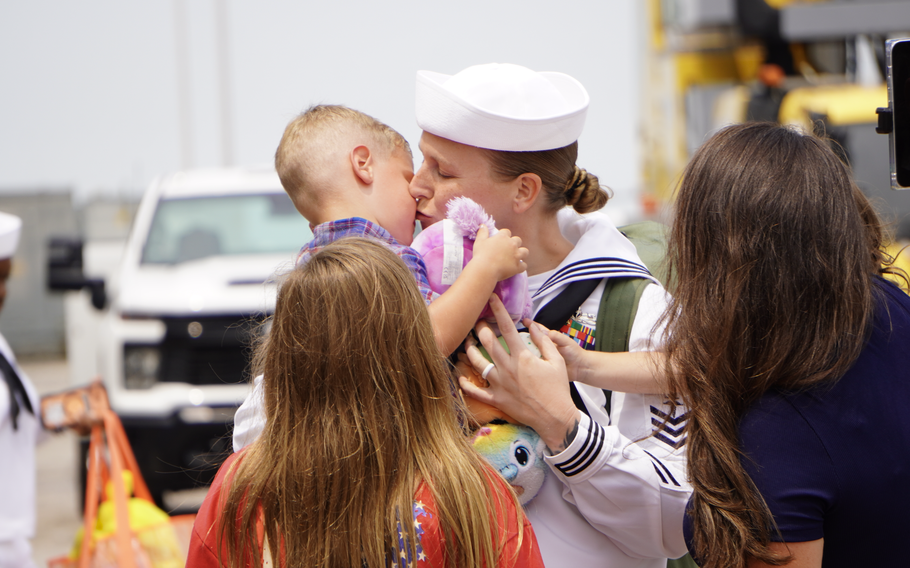 A sailor kisses a child.